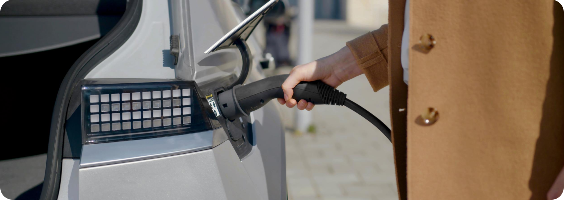 Electric car charged at home, with visible photovoltaic panels and smart home elements, symbolizing optimization and control over energy.