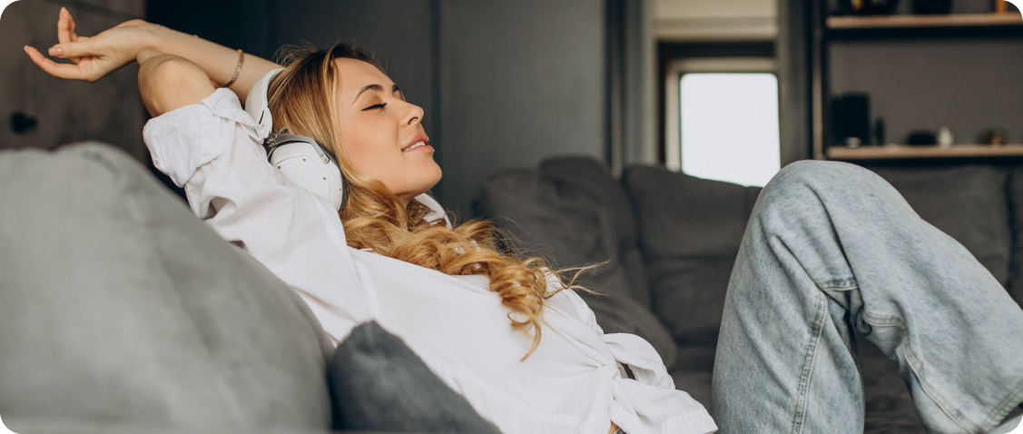 Exhausted man lying helplessly on the couch with a phone, illustrating why resting on the couch does not work in the fight against chronic stress