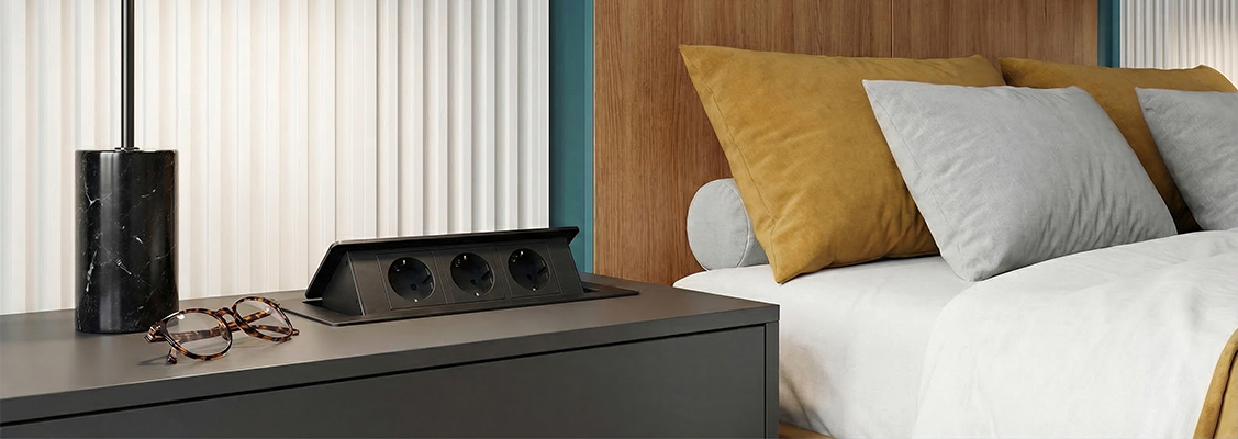 Eleganckie gniazdo obrotowe wpuszczane w drewniany blat biurka, zlicowane z powierzchnią roboczą, zapewniające estetykę i funkcjonalność w nowoczesnym biurze.