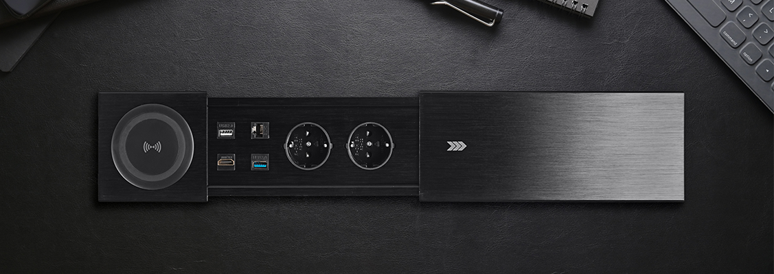 Nowoczesne gniazdko meblowe wpuszczane w blat z wbudowaną ładowarką indukcyjną, zamontowane w ergonomicznym biurku