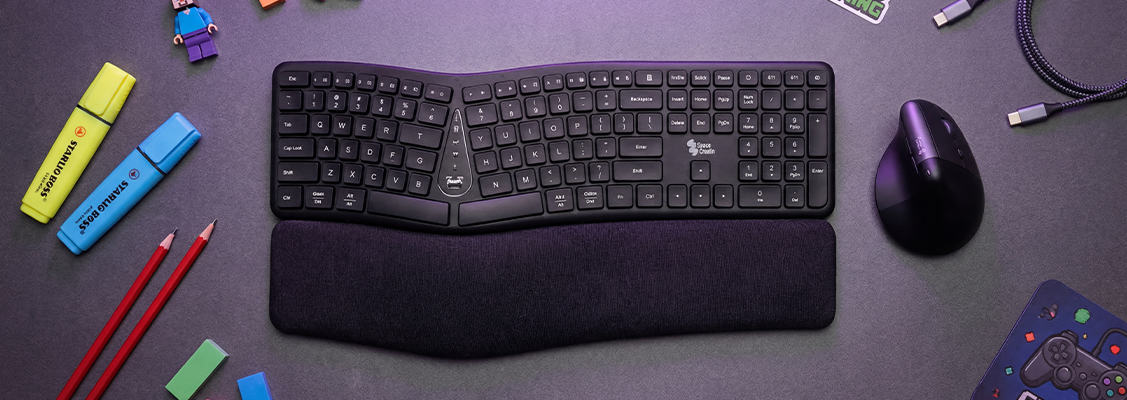 Profilowana klawiatura ergonomiczna na nowoczesnym biurku komputerowym, idealna jako praktyczny prezent na komunię dla dziecka dbającego o zdrowie dłoni i nadgarstków.